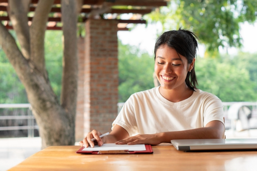 Student studying outside at table smiling