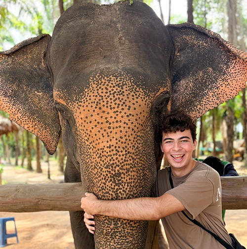 Young man hugging a friendly elephant.