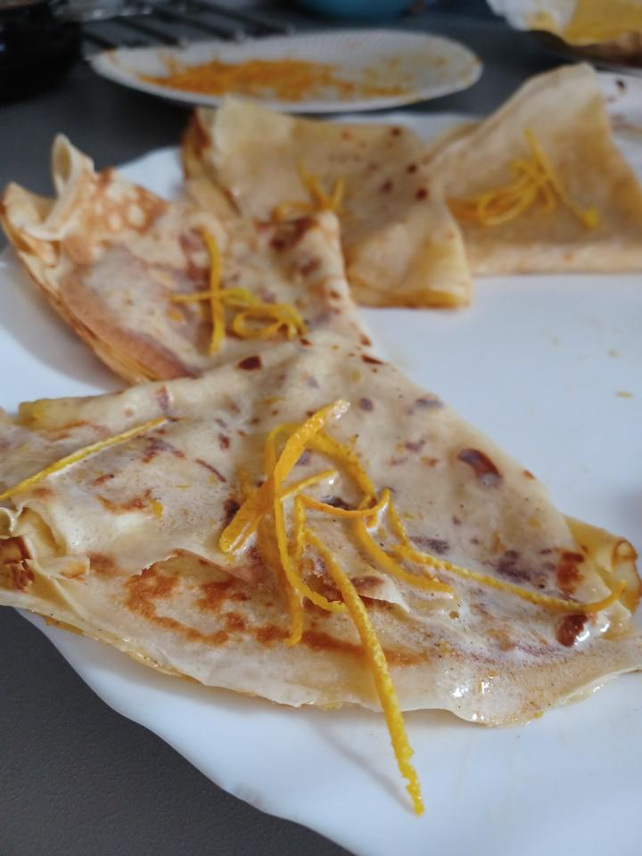 two crepes on a plate with orange peels on top