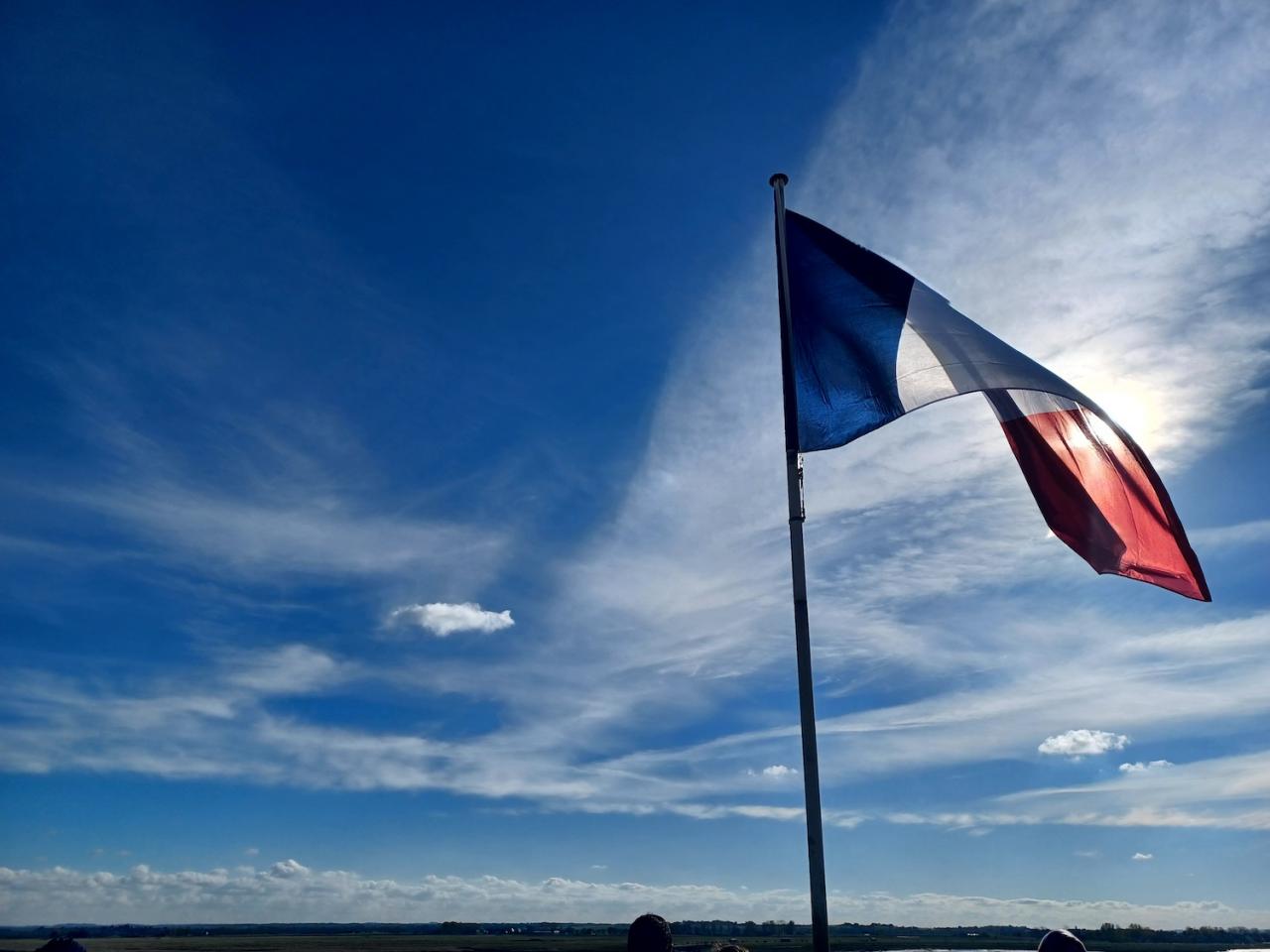 french flag against sky with sun behind
