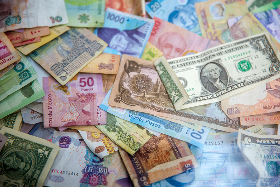 Money from different countries displayed all over a table.