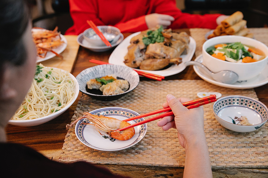 Woman using chopsticks to eat a large shrimp. 