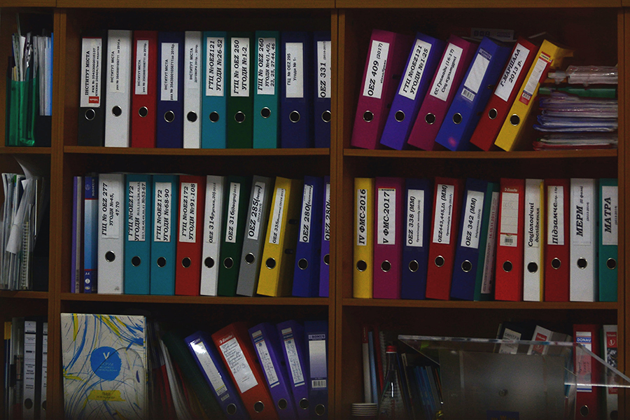 Assortment of colored binders on a bookshelf.